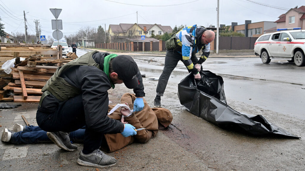 A communal worker cuts the rope of the corpse of a man in Buch