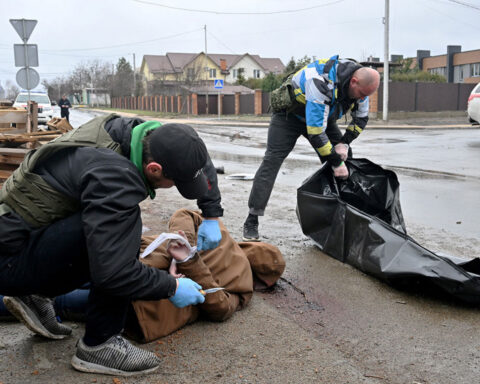 A communal worker cuts the rope of the corpse of a man in Buch