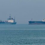 Global oil supply route risk with military escort ships accompanying oil tankers through high-risk waters