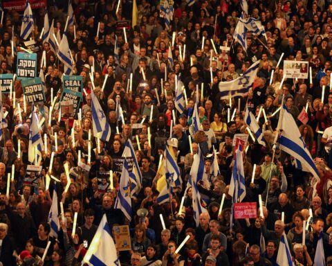 Middle East conflict update with protesters holding peace signs during rally in Tel Aviv