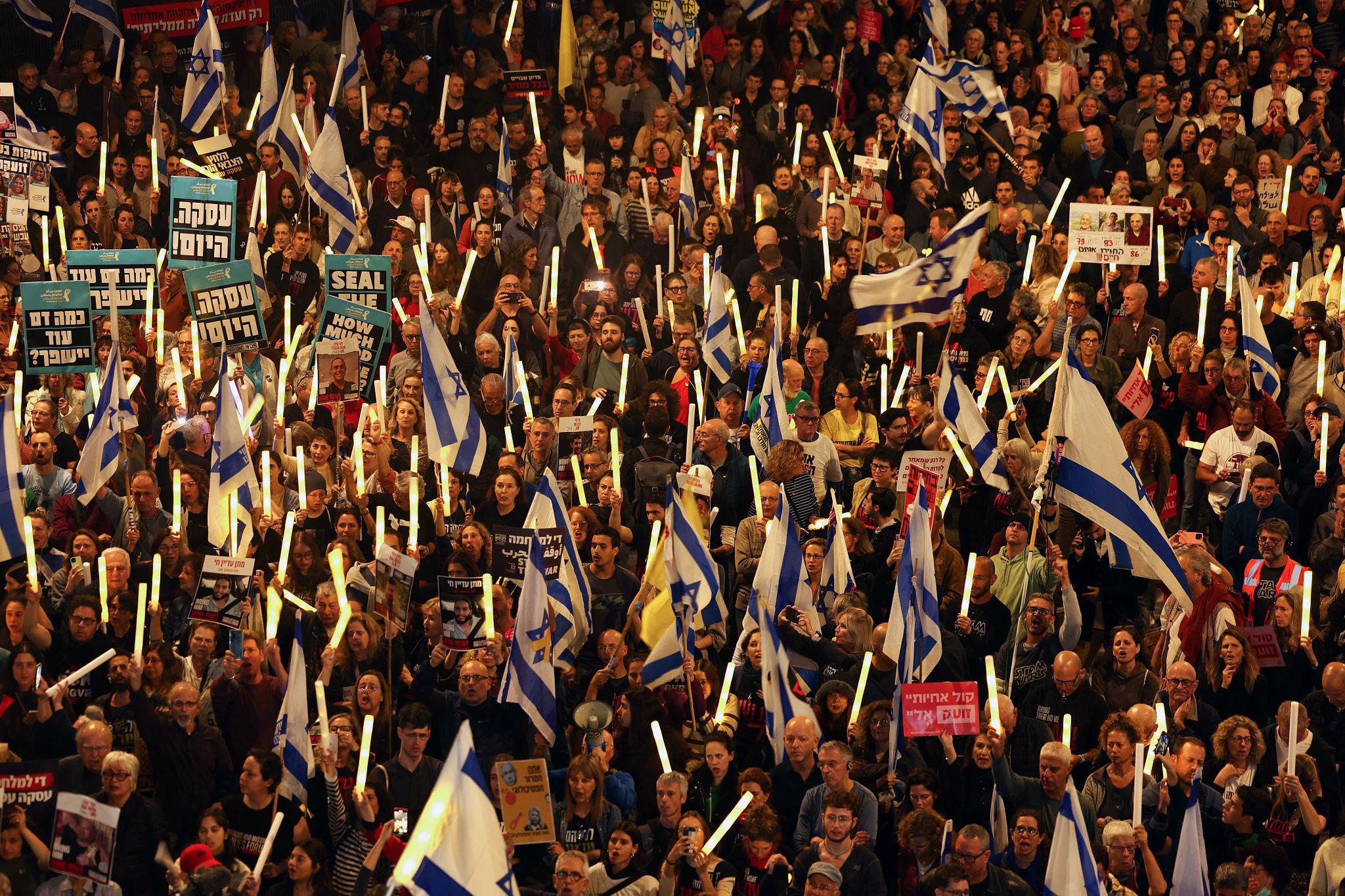 Middle East conflict update with protesters holding peace signs during rally in Tel Aviv
