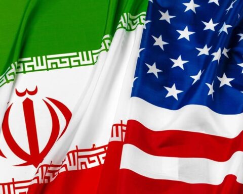Diplomats meet during Iran US negotiations with US and Iran flags displayed